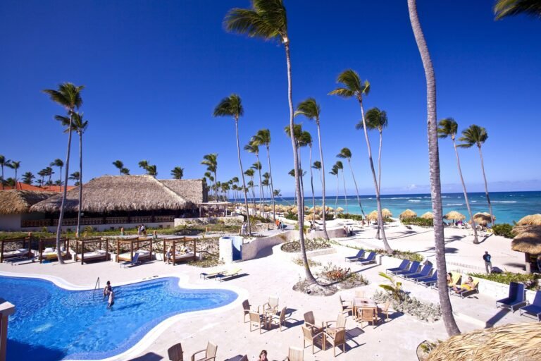 Piscina, palmeras y playa de un resort en Punta Cana